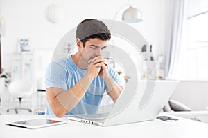 Sad man sitting at desk at home with a laptop. Freelance and selfemployment concept photo