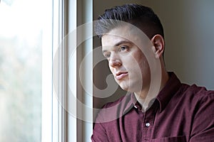 Sad Man Suffering From Depression Looking Out Of Window