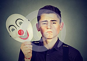 Sad man taking off happy clown mask. Split personality