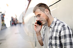 Sad man talks on phone in a solitary street