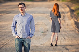 Sad man and woman stand on the dirt road