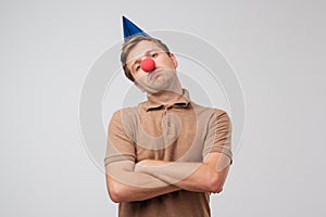 Sad mature man with red clown nose looking sadly at camera.