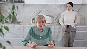 Sad mature woman arguing with her distressed daughter in kitchen