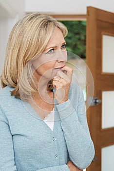 Sad Mature Woman Suffering From Agoraphobia Looking Out Of Open photo