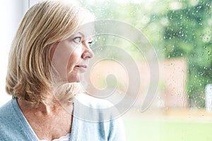 Sad Mature Woman Suffering From Agoraphobia Looking Out Of Window photo