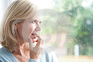 Sad Mature Woman Suffering From Agoraphobia Looking Out Of Window photo