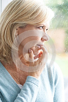 Sad Mature Woman Suffering From Agoraphobia Looking Out Of Window photo