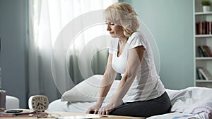 Sad middle-aged lady sitting bed, health problems, thoughtful female pensioner