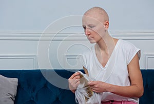 Sad middle aged woman cancer survivor holds wig in her hands