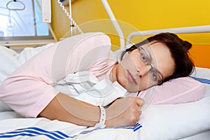Sad middle-aged woman lying in hospital