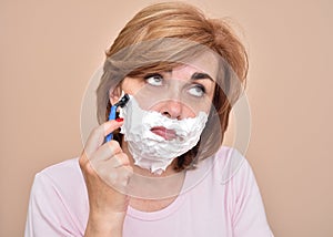 Sad middle aged woman shaving her face with a razor