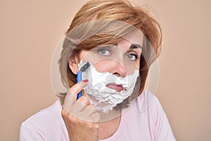 Sad middle aged woman shaving her face with a razor