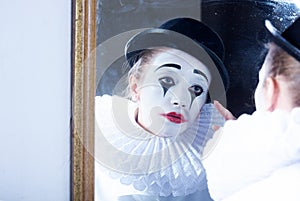 Sad mime Pierrot looking at the mirror