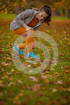 sad modern woman in fitness clothes in park got leg injury