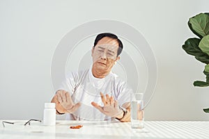 Sad mood. Low angle shot of an upset elderly man sitting while taking his medication