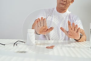 Sad mood. Low angle shot of an upset elderly man sitting while taking his medication