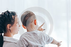 Sad mother sitting next to the window with baby