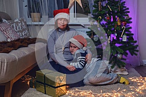 Sad mother and son at the Christmas tree in the night light garlands. F