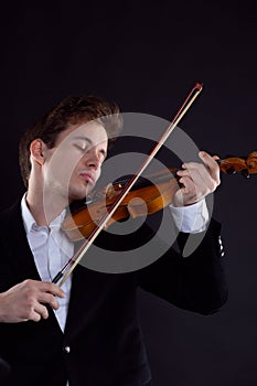 Sad music, the concept of bad luck. The young violinist is elegantly dressed, shaken, and plays the violin.