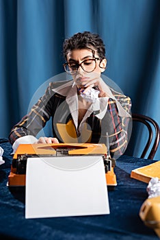 sad newswoman sitting near vintage typewriter