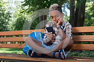 Sad nice boy looking at his smartphone screen