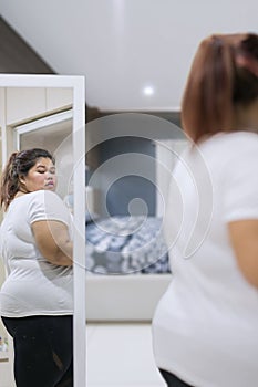 Sad obese woman looking at her big body