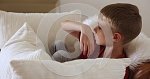 Sad offended boy sitting on armchair looks disgruntled and upset