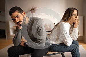 Sad offended unhappy young arabic man ignores european woman sit on sofa back to back