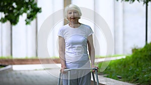 Sad old female with walking frame at sunny hospital park, ineffective treatment