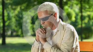 Sad old man with cane and dark glasses thinking on bench, lack of state support