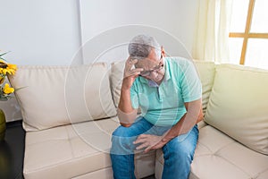 A sad old man with a headache who seems desperate and lonely at home