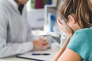 Sad patient visiting doctor. Young woman with stress or burnout getting help from medical professional or therapist. photo