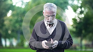 Sad pensioner holding empty wallet, retirement poverty, financial crisis, credit