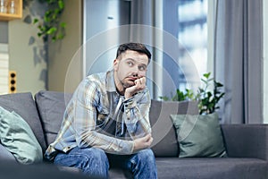 Sad and pensive man sitting on the couch at home