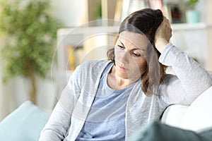 Sad pensive middle age woman looking down at home