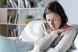 Sad pensive middle age woman looking down sitting at home photo