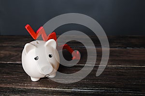 Sad piggy bank and down arrow. Savings and reserves decrease. Inflation, depreciation of assets. Falling income, lower wages.