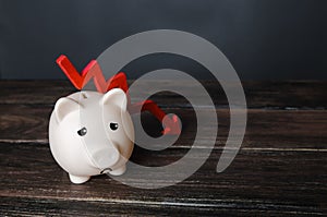 Sad piggy bank and down arrow. Savings and reserves decrease. Inflation, depreciation of assets. Falling income, lower wages. photo