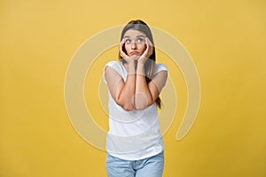 A sad pleading look of a young attractive woman isolated on yellow background Studio portrait hands linked together