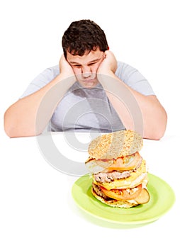 Sad, plus sized and man with a burger meal in a studio for lunch, supper or dinner for weight gain. Depression, upset