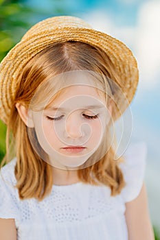sad portrait of a little girl with blonde hair in a straw hat. children's whims