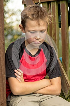 Sad pre-teen boy sitting outside