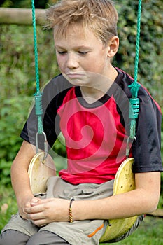 Sad pre-teen boy sitting on a swing