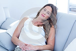 Sad pregnant woman leaning on sofa