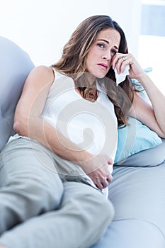 Sad pregnant woman relaxing on sofa