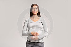Sad Pregnant Woman Touching Belly Standing, Studio Shot