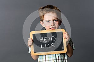 Sad preschool kid protecting from head lice behind school slate