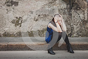 Sad pretty girl sitting on sidewalk