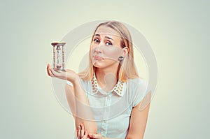 Sad pretty woman holding a sand timer clock looking upset at you