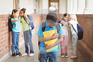 Sad pupil being bullied by classmates at corridor